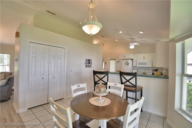 dining space with lofted ceiling, light tile patterned flooring, visible vents, and baseboards