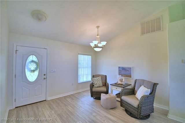 entryway featuring baseboards, visible vents, vaulted ceiling, light wood-style floors, and a chandelier