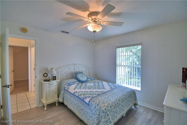 bedroom with a ceiling fan, visible vents, light wood-style flooring, and baseboards