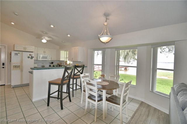 dining room featuring baseboards, vaulted ceiling, a wealth of natural light, and light tile patterned flooring