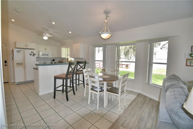 dining space featuring a wealth of natural light, lofted ceiling, light tile patterned flooring, and baseboards