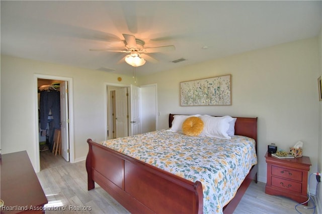 bedroom featuring light wood finished floors, visible vents, a spacious closet, ceiling fan, and baseboards