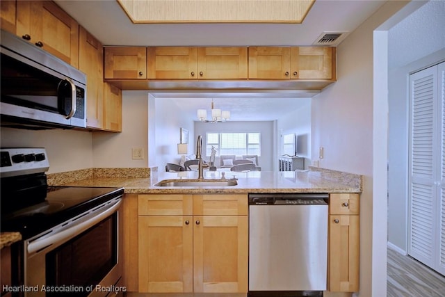 kitchen featuring appliances with stainless steel finishes, visible vents, a sink, and light brown cabinets