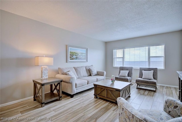 living area with a textured ceiling, baseboards, and light wood-style floors