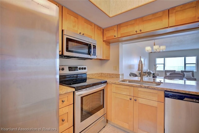 kitchen with light stone counters, light tile patterned floors, light brown cabinetry, appliances with stainless steel finishes, and a sink