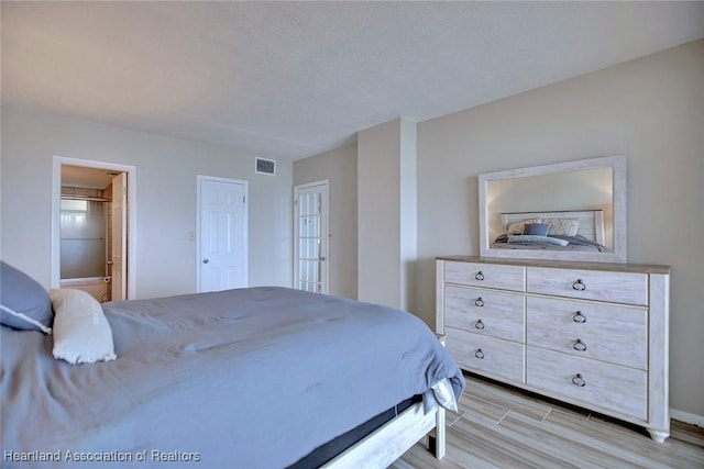 bedroom with light wood-style floors and visible vents