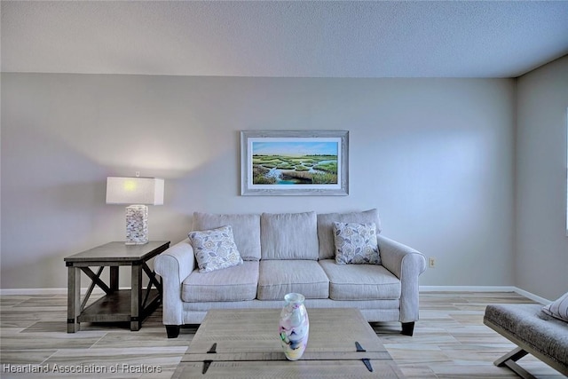 living area with a textured ceiling, light wood-style flooring, and baseboards