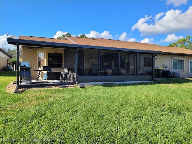 rear view of house with central AC, a sunroom, a lawn, and a patio