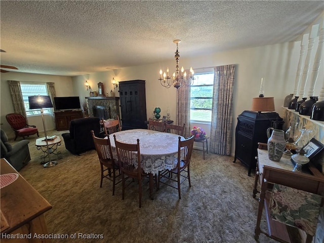 dining area featuring ceiling fan with notable chandelier, carpet floors, and a textured ceiling