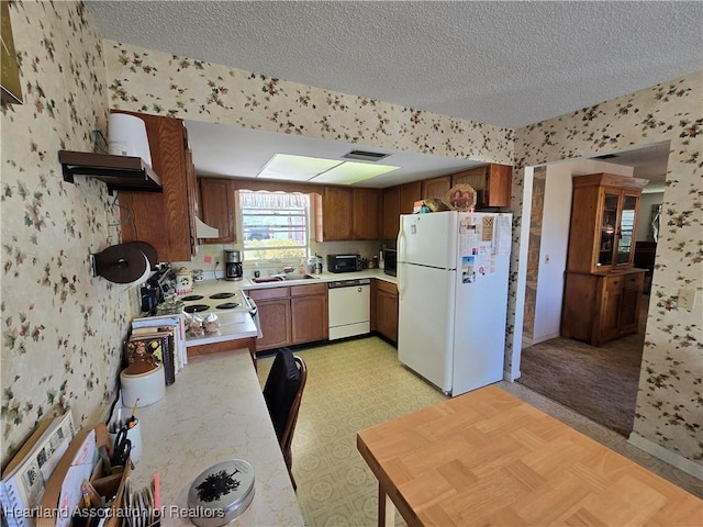 kitchen featuring sink, white appliances, and a textured ceiling