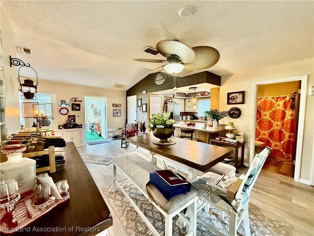 dining space with lofted ceiling, light wood-style flooring, and visible vents