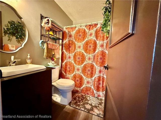 bathroom featuring a shower with shower curtain, toilet, a textured ceiling, vanity, and wood finished floors