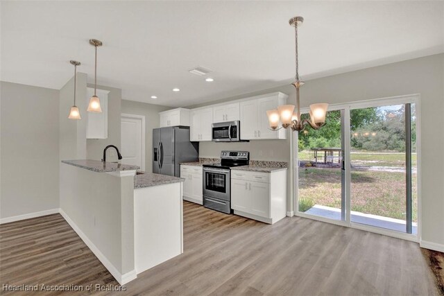 kitchen with white cabinets, pendant lighting, kitchen peninsula, and appliances with stainless steel finishes