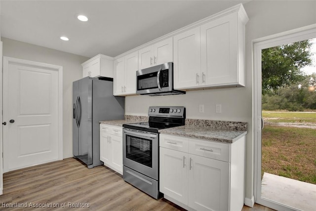 kitchen featuring light stone countertops, light wood-type flooring, white cabinetry, and appliances with stainless steel finishes