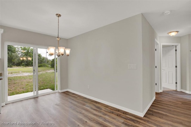 unfurnished dining area featuring dark hardwood / wood-style flooring and a chandelier