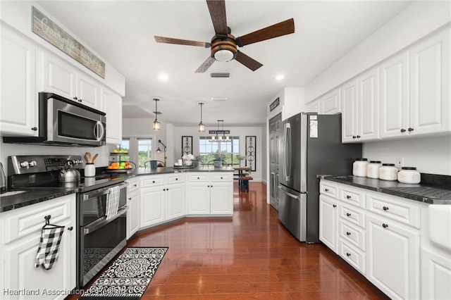 509 Bear Rd, Lake Placid, FL 33852 - kitchen featuring appliances with stainless steel finishes, a peninsula, dark countertops, ceiling fan, and white cabinetry