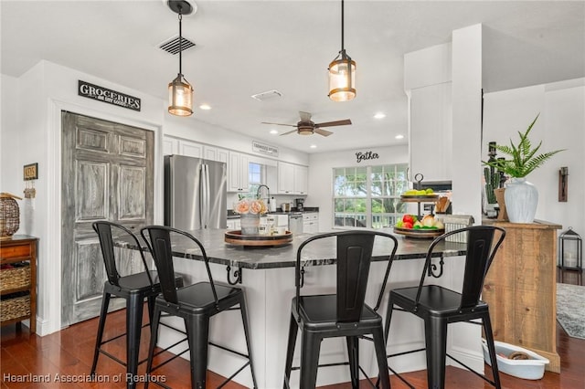 509 Bear Rd, Lake Placid, FL 33852 - kitchen with freestanding refrigerator, dark countertops, white cabinetry, a peninsula, and a kitchen breakfast bar