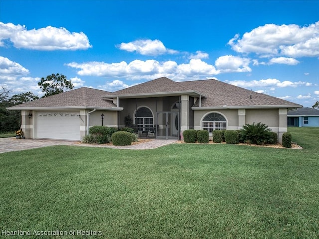 view of front of property featuring a sunroom, a garage, and a front lawn