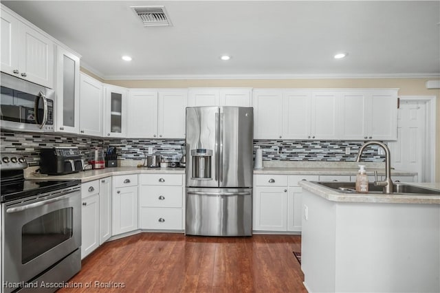 kitchen with sink, dark wood-type flooring, appliances with stainless steel finishes, white cabinetry, and ornamental molding