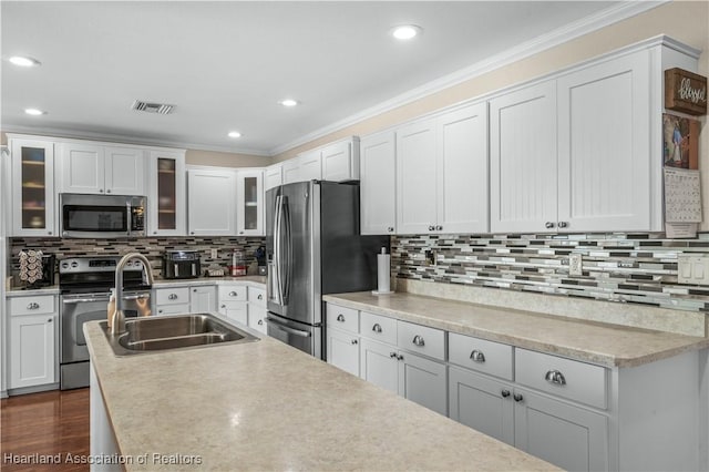 kitchen with sink, crown molding, appliances with stainless steel finishes, white cabinets, and decorative backsplash