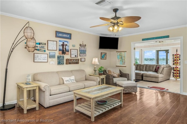 living room featuring dark wood-type flooring, ornamental molding, and ceiling fan