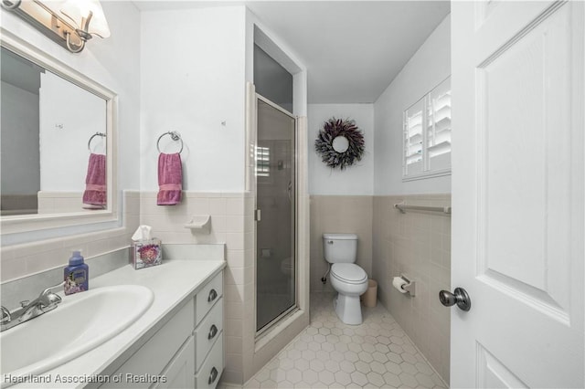 bathroom featuring a shower with door, tile walls, vanity, tile patterned floors, and toilet