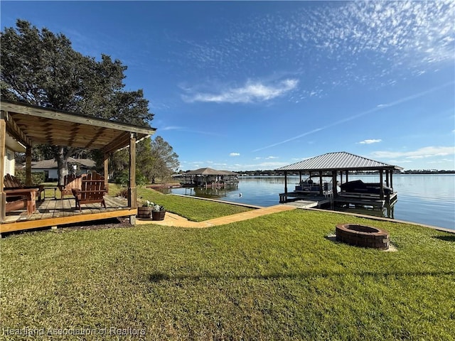 dock area with a lawn, a water view, and an outdoor fire pit