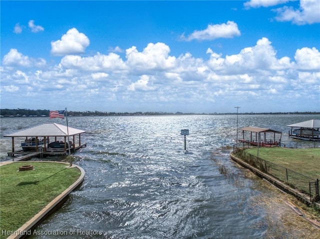 view of dock with a water view and a lawn