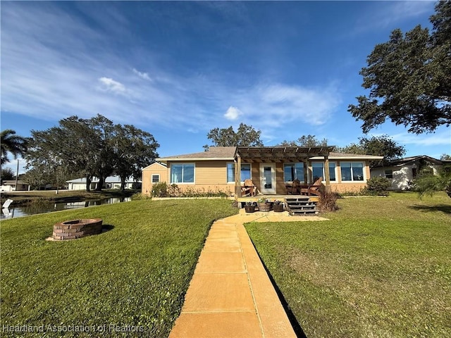 rear view of property featuring a water view, a yard, a pergola, and a fire pit