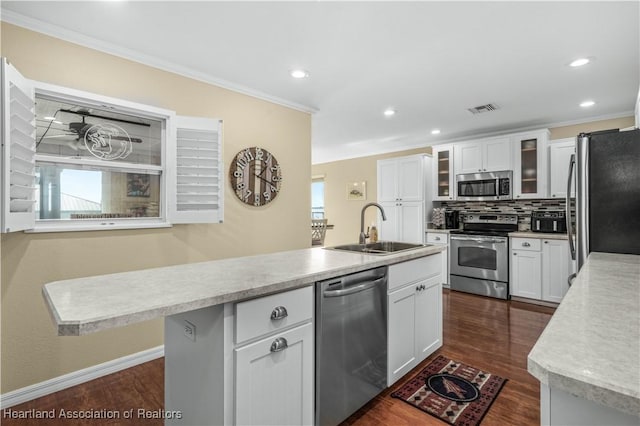 kitchen featuring appliances with stainless steel finishes, an island with sink, sink, white cabinets, and crown molding