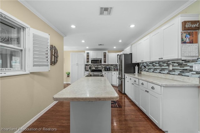 kitchen featuring sink, ornamental molding, an island with sink, stainless steel appliances, and white cabinets