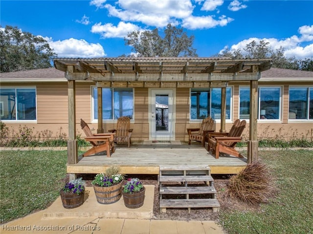 back of property featuring a lawn, a deck, and a pergola