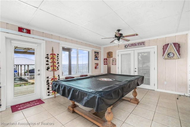 recreation room with light tile patterned floors, plenty of natural light, french doors, and a water view