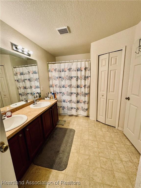 bathroom with vanity, a textured ceiling, and walk in shower