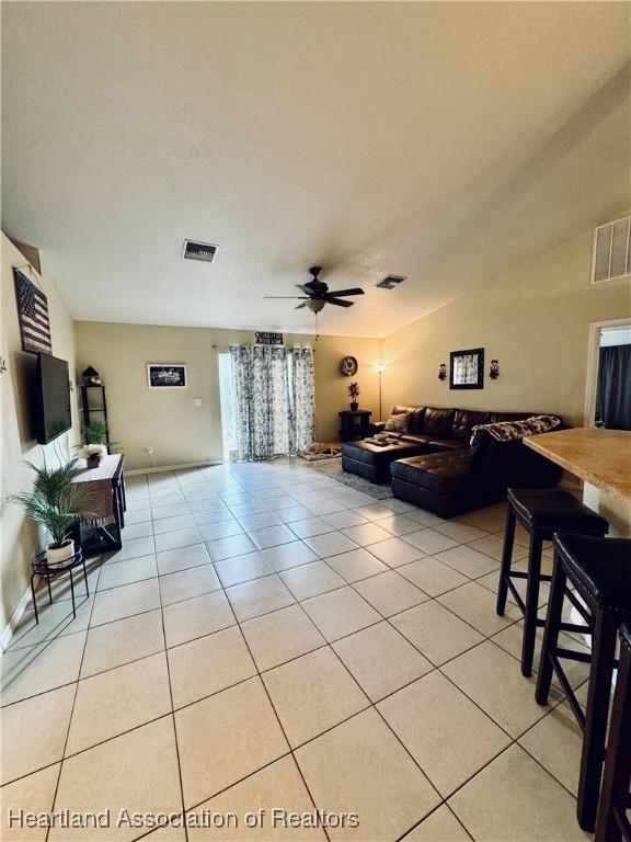 tiled living room with lofted ceiling and ceiling fan