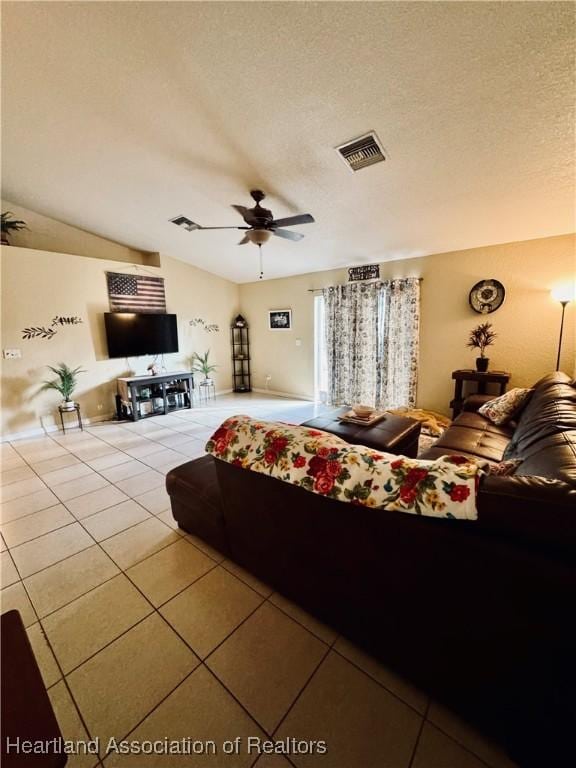 bedroom featuring ceiling fan, vaulted ceiling, a textured ceiling, and light tile patterned floors