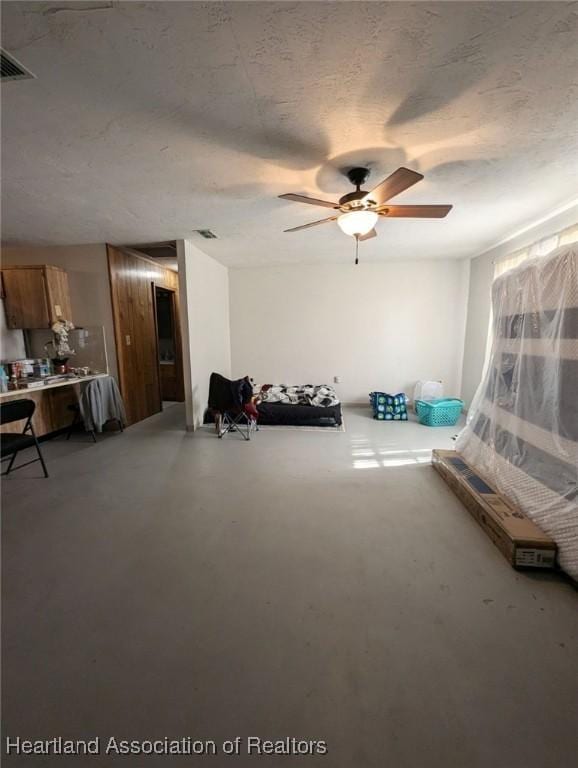 miscellaneous room with concrete flooring, a textured ceiling, and ceiling fan