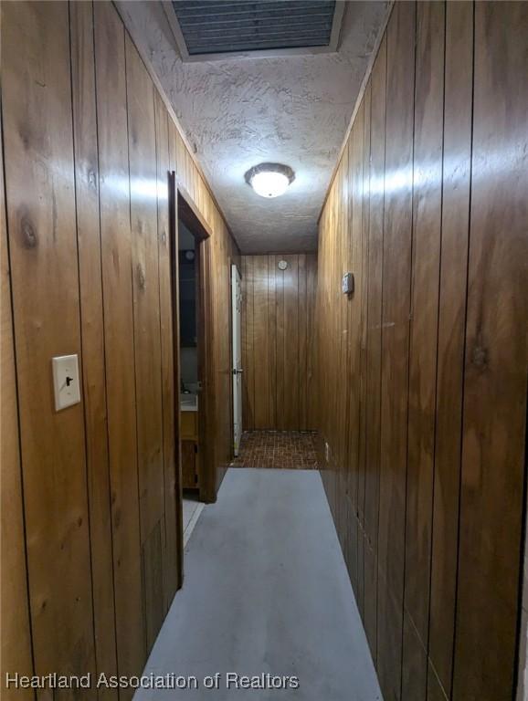 hall with wooden walls and a textured ceiling