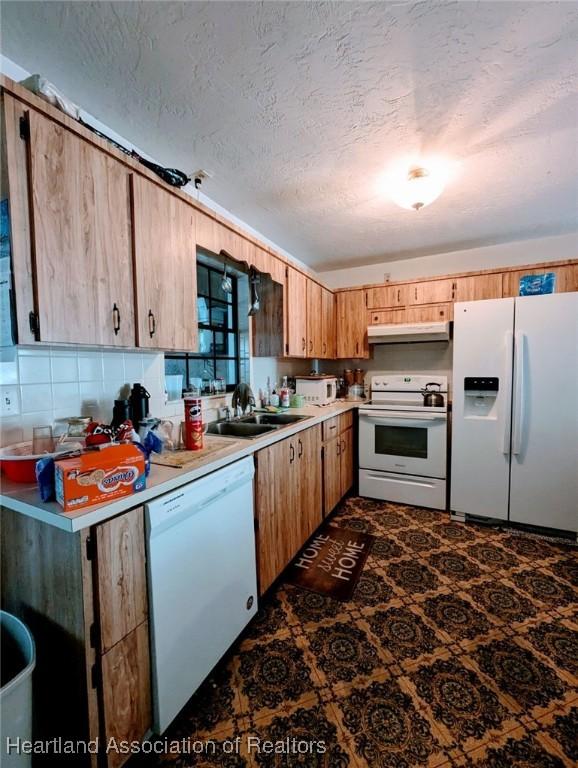 kitchen with a textured ceiling, decorative backsplash, sink, and white appliances