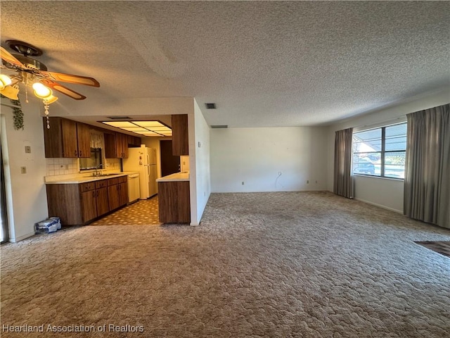 kitchen featuring sink, ceiling fan, white refrigerator, light carpet, and decorative backsplash