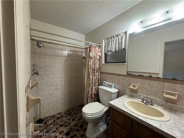 bathroom with tile walls, a shower with shower curtain, vanity, a textured ceiling, and toilet