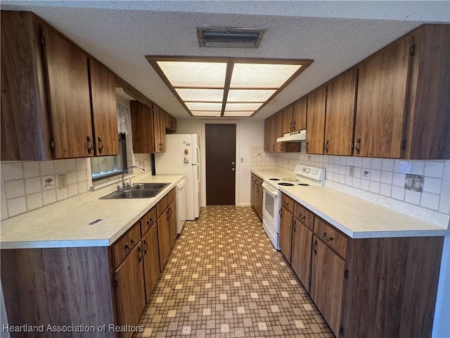 kitchen featuring sink, white appliances, a textured ceiling, and backsplash