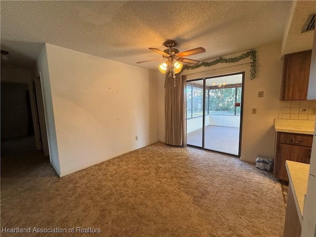 interior space with a textured ceiling, light colored carpet, and ceiling fan