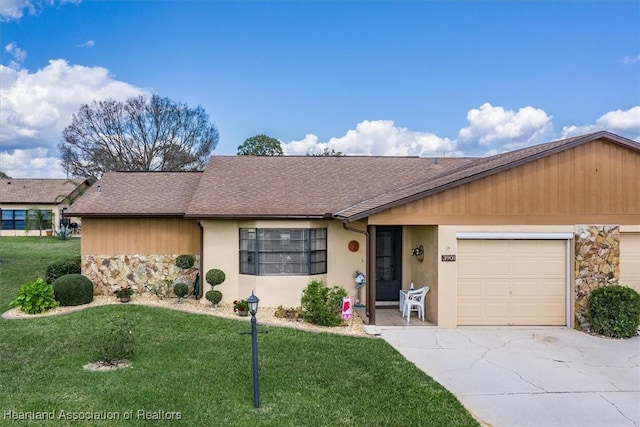 single story home featuring concrete driveway, stone siding, an attached garage, a yard, and stucco siding