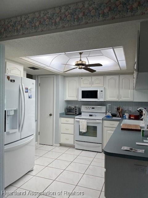 kitchen featuring white appliances, ceiling fan, sink, light tile patterned floors, and white cabinets