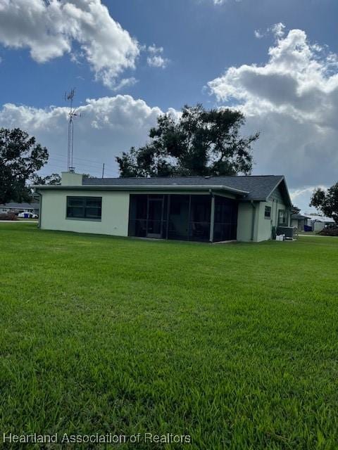 rear view of property with a sunroom and a lawn