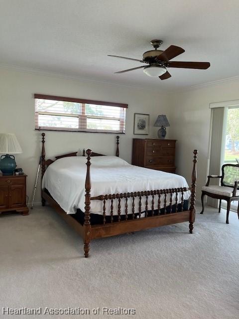 carpeted bedroom with ceiling fan and ornamental molding