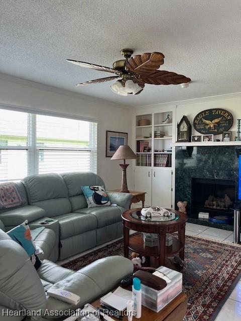 living room featuring a fireplace, light tile patterned floors, a textured ceiling, and ornamental molding