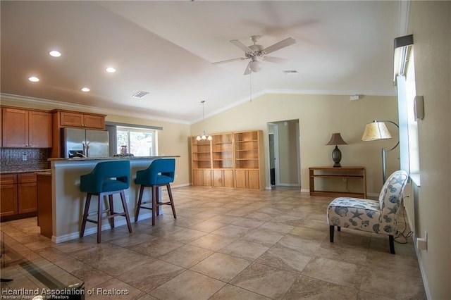 kitchen featuring lofted ceiling, backsplash, crown molding, a kitchen breakfast bar, and stainless steel fridge with ice dispenser