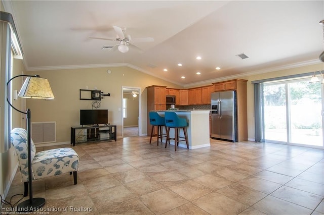 kitchen with ceiling fan, appliances with stainless steel finishes, a kitchen breakfast bar, lofted ceiling, and ornamental molding